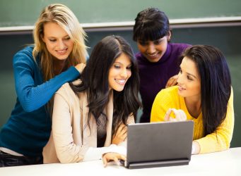 college students discussing project on laptop in classroom