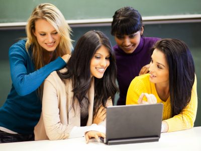 college students discussing project on laptop in classroom